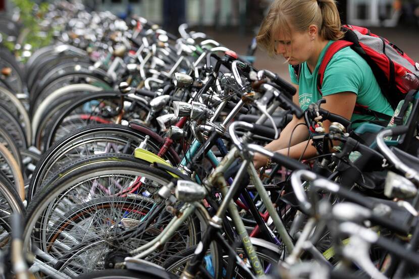 Vrouw parkeert fiets in fietsenrek