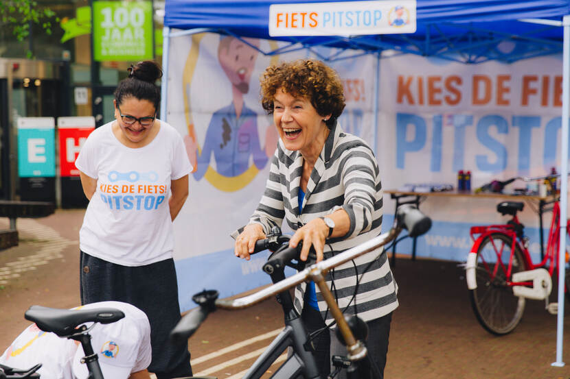foto van een lachende vrouw met fiets bij een fietspitstop